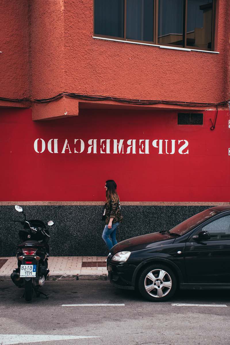 machine woman walking between building and vehicles spoke