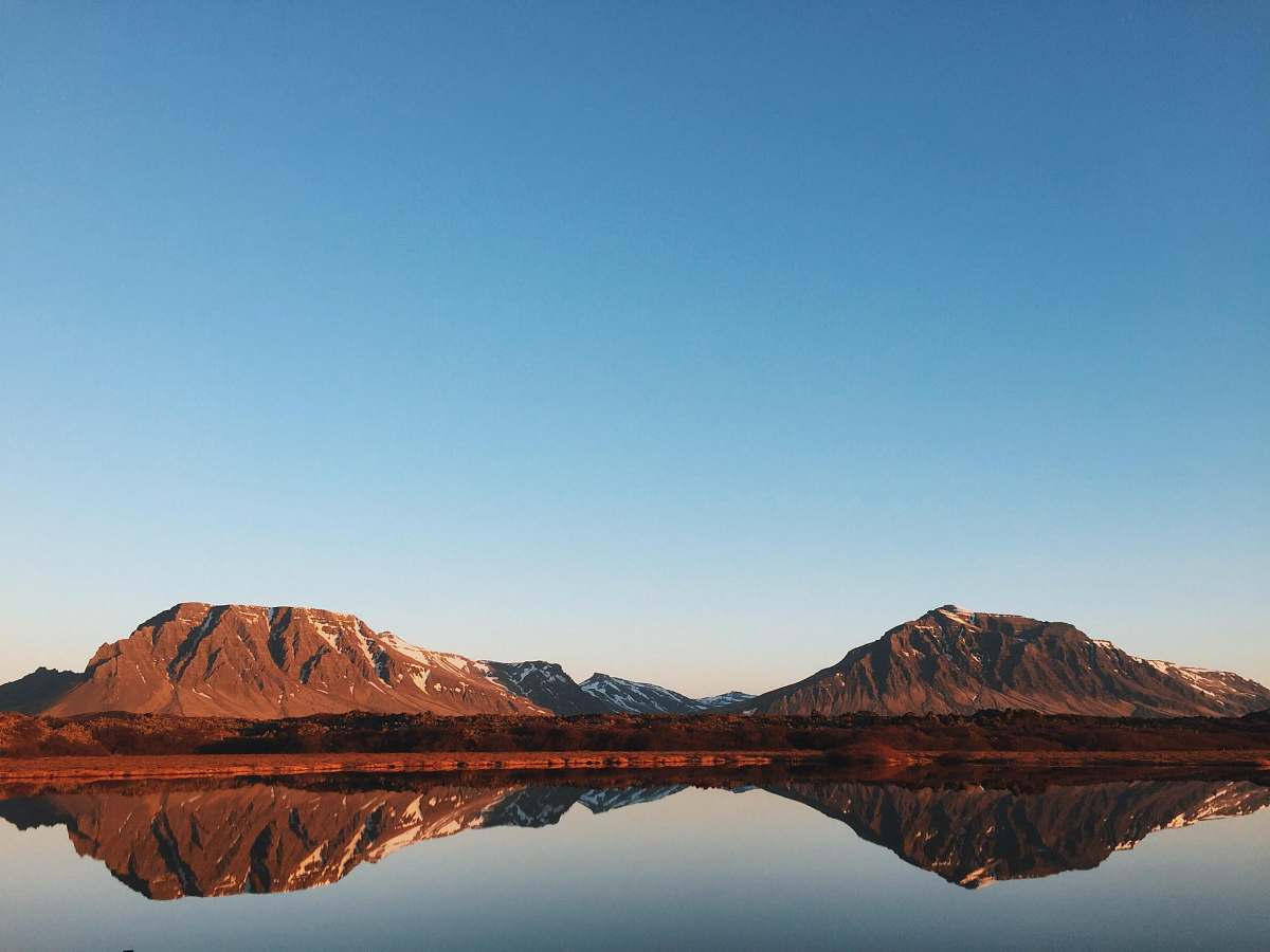 mountain calm lake reflecting rock cliffs and clear blue skies mountain range