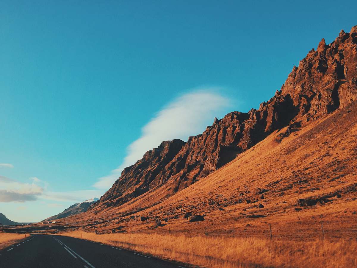 desert concrete road beside mountain under blue sky mountain