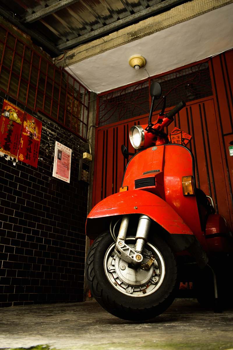 wheel orange scooter parked near black concrete building vehicle