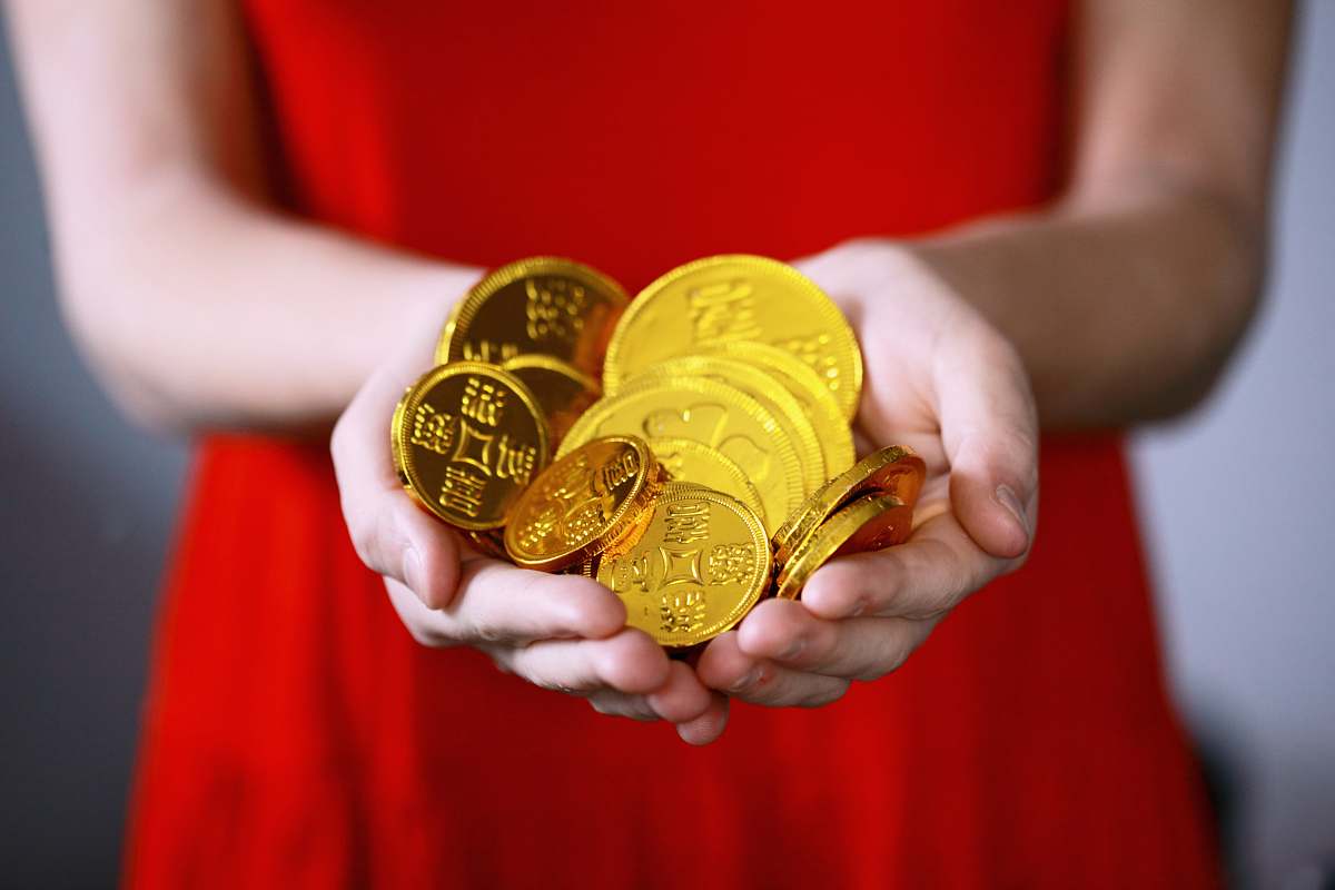 gold person holding gold-colored ching coins coin