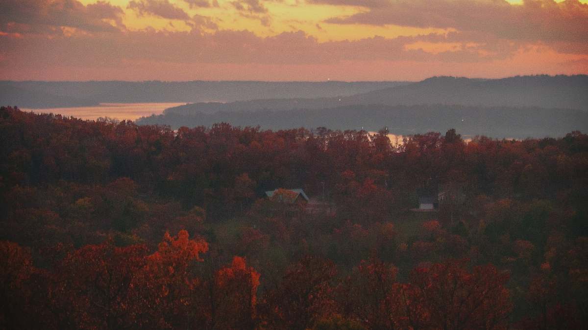 outdoors aerial photography of house surrounded by trees beside shore during daytime dawn