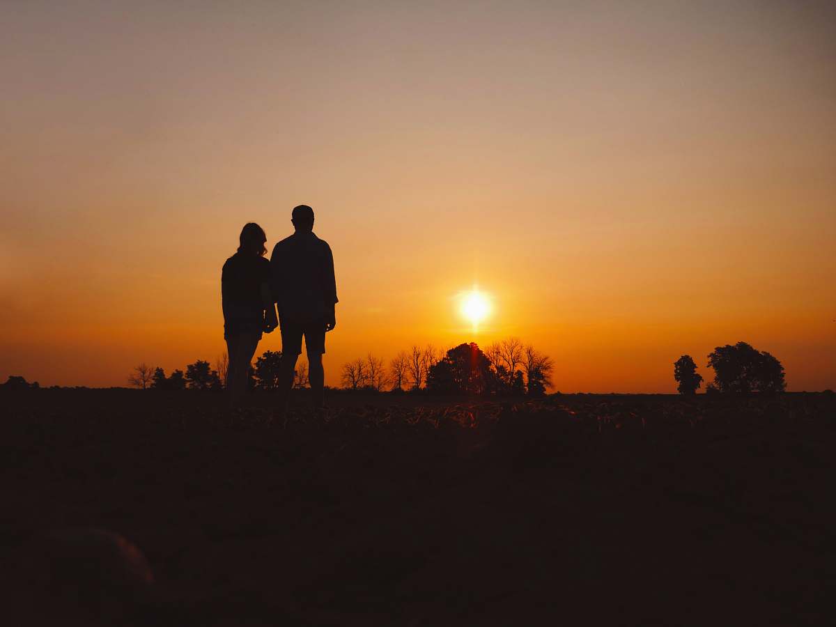 human couple stands on field during golden hour person