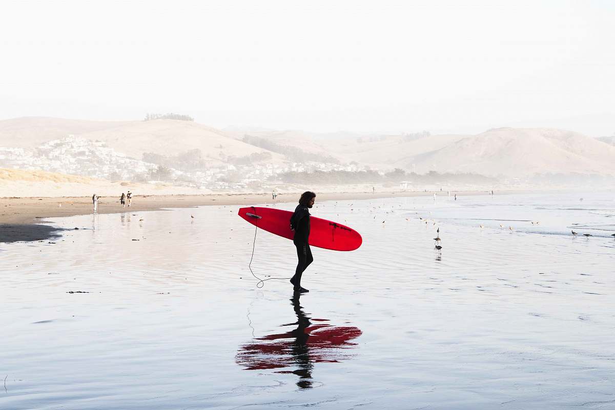 surfboard person on body of water carrying red surfboard water