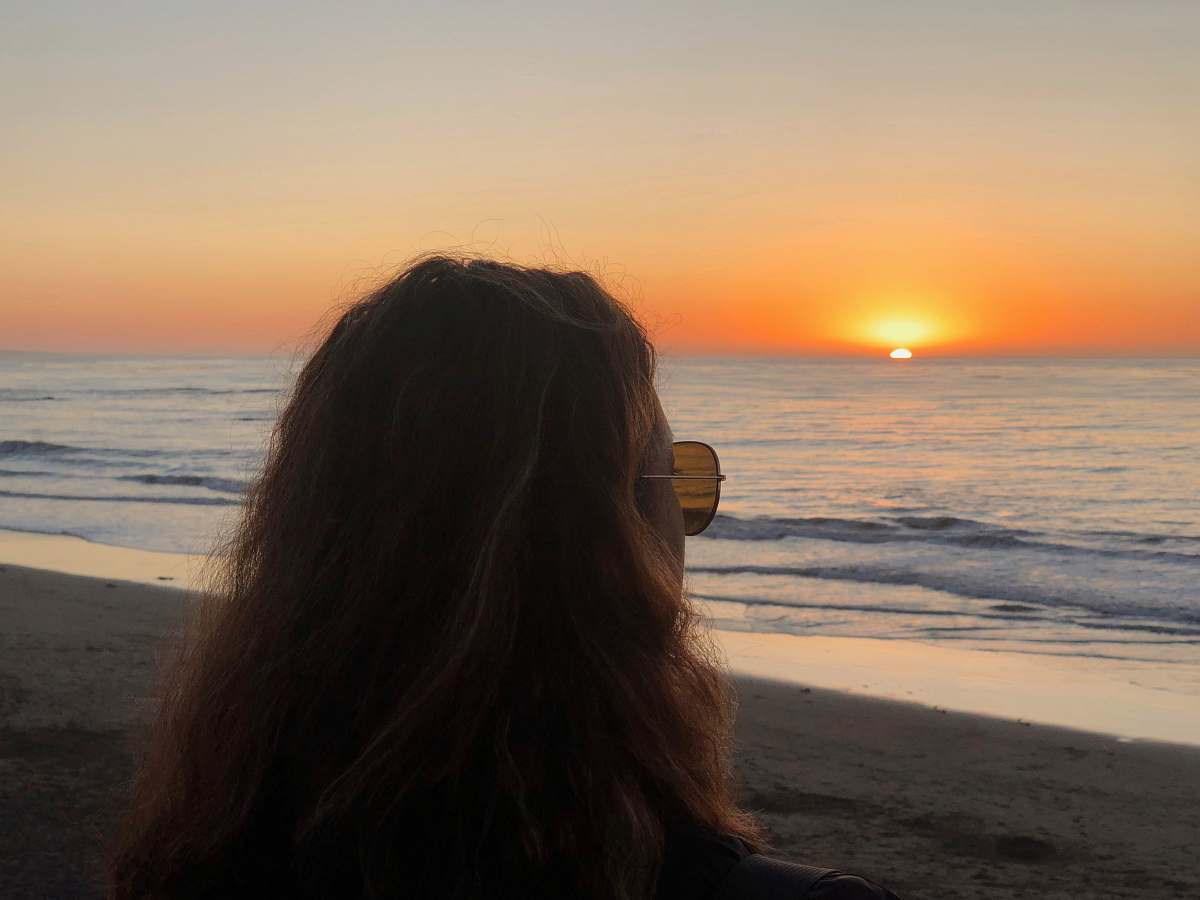 person photo of woman wearing brown sunglass looking at sunset during sunset outdoors