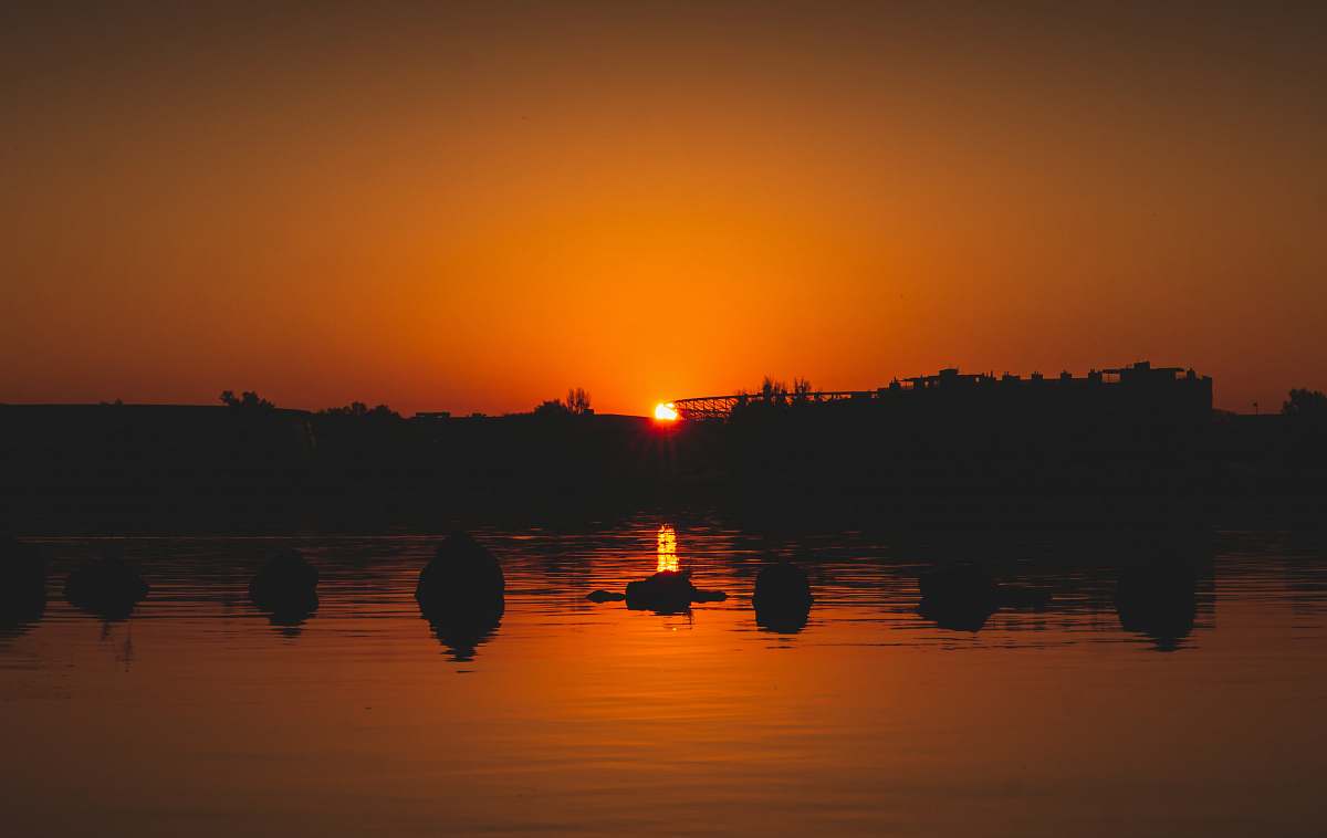 outdoors silhouette of body of water under orange sky dawn