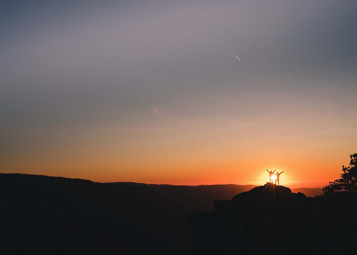 sunset silhouette of couple on cliff during golden hour sunrise