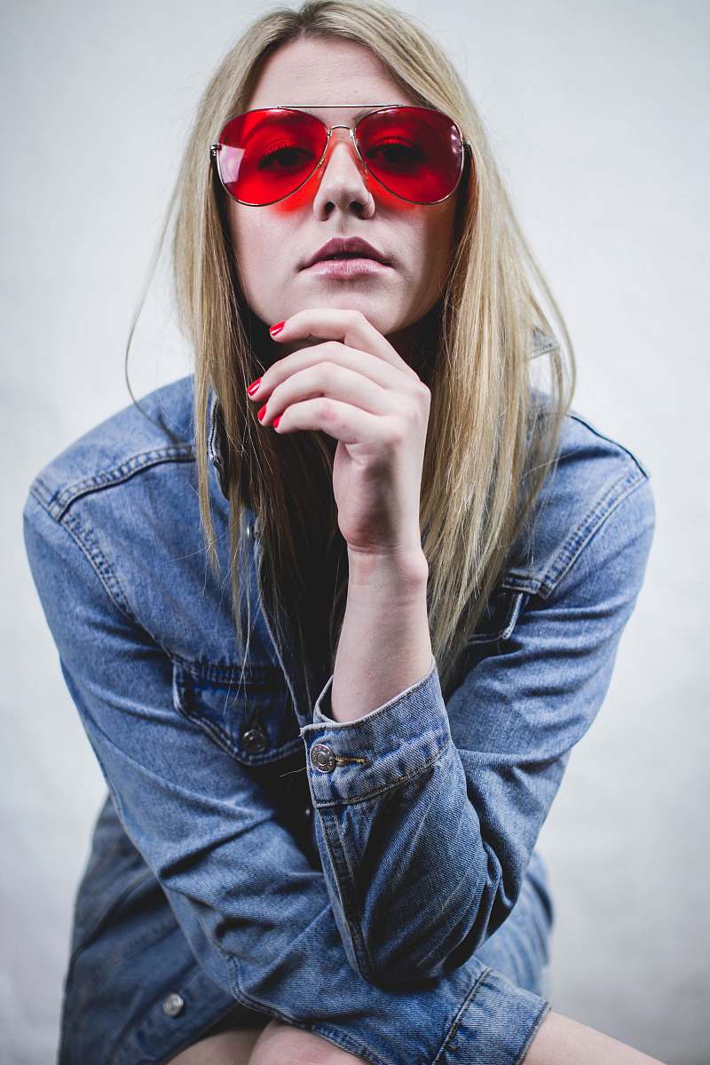 person woman in blue denim jacket wearing red sunglasses and red manicure with hands on chin human