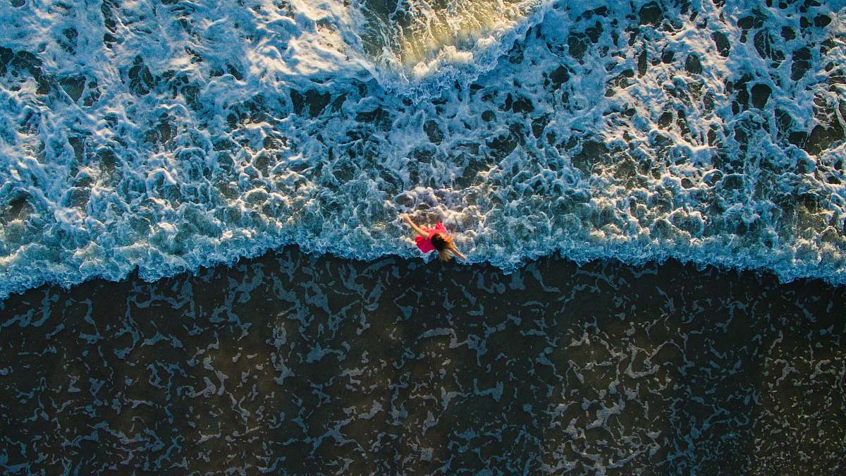water aerial photo of woman standing on shore beach