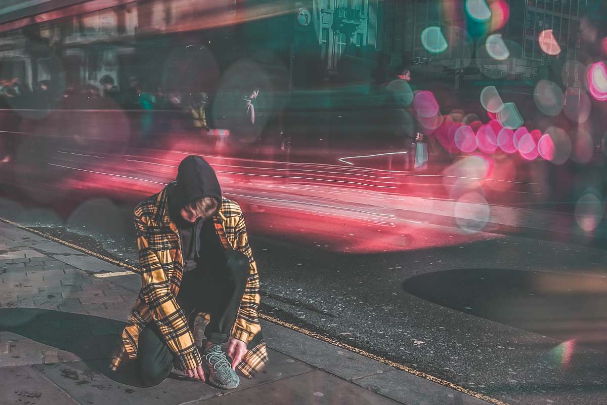 people man lacing shoes beside street timelapse photography human