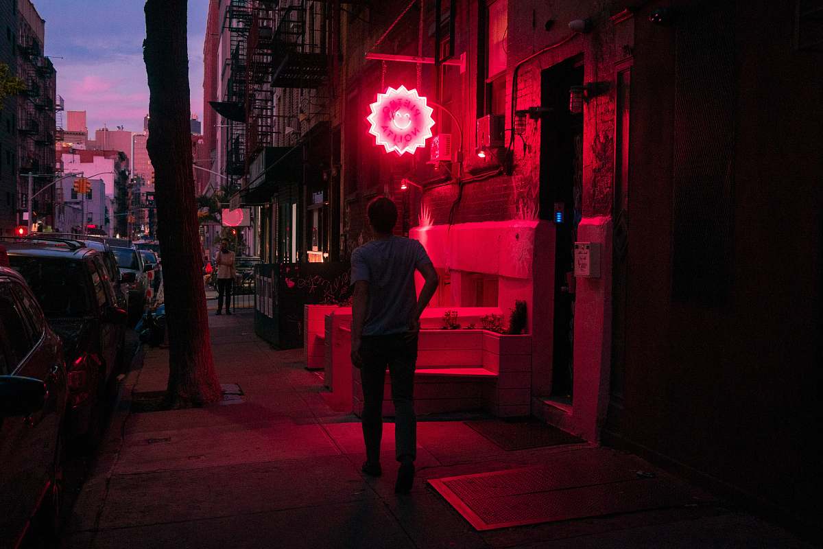 human people walking on pathway near buildings and different vehicles on road during night time lighting