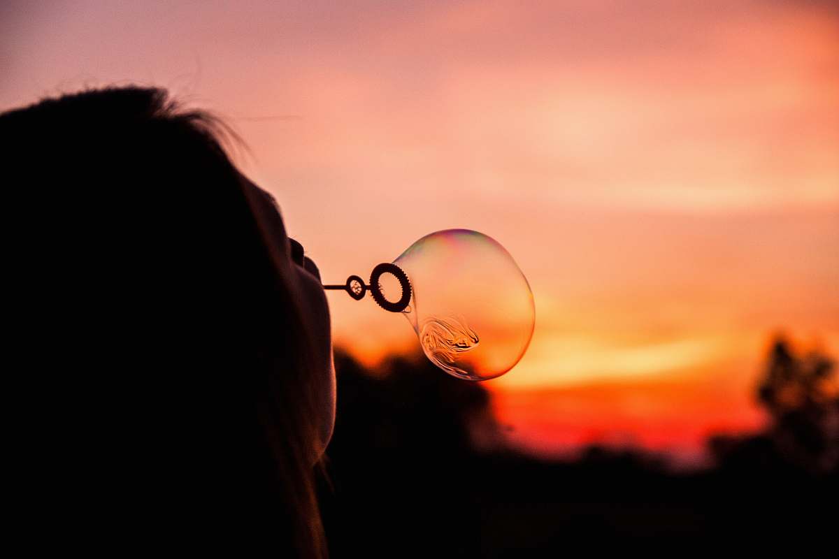bubble shallow focus photography of person blowing bubble balloon woman