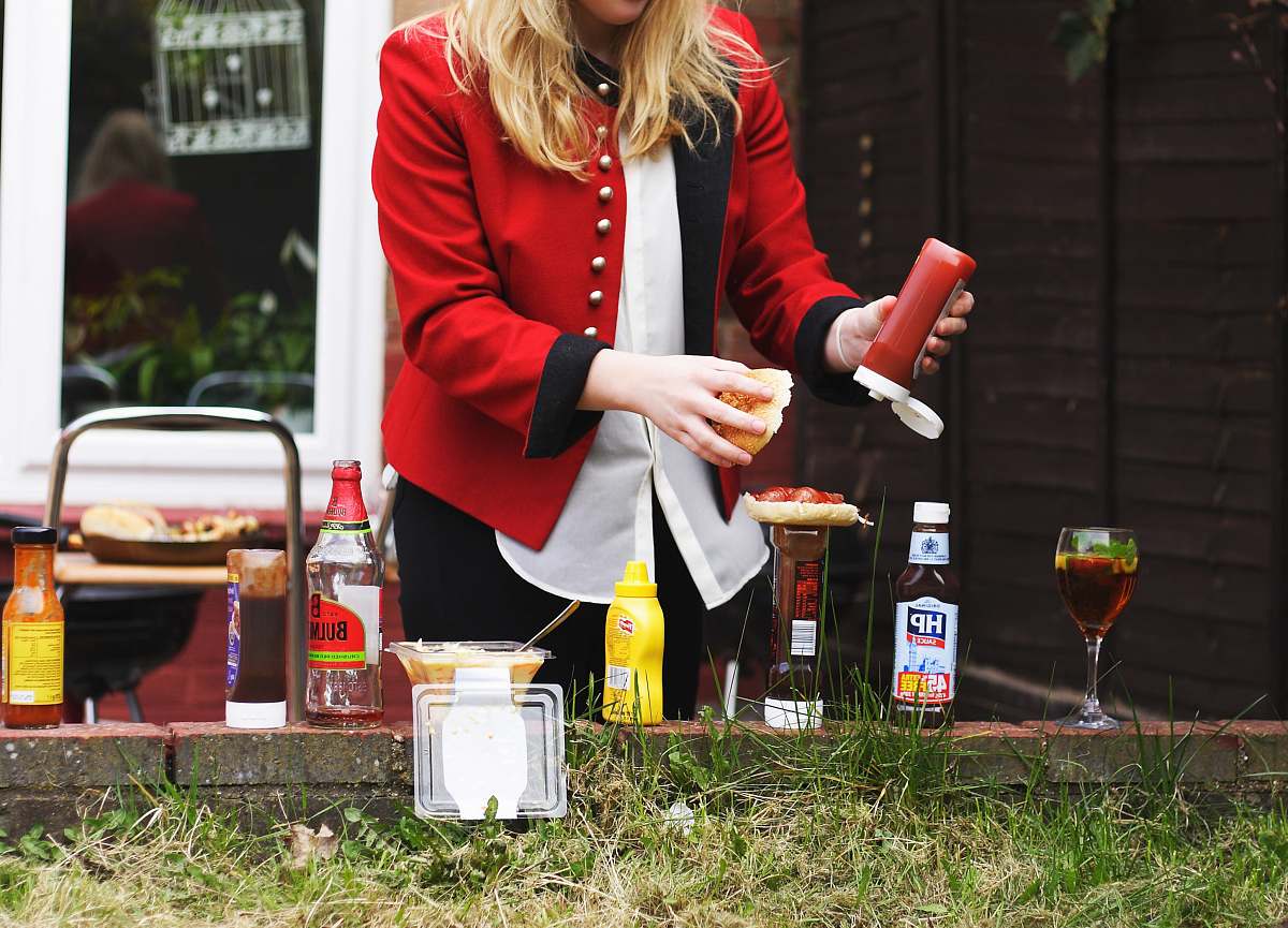 people woman putting red sauce on hamburger bbq