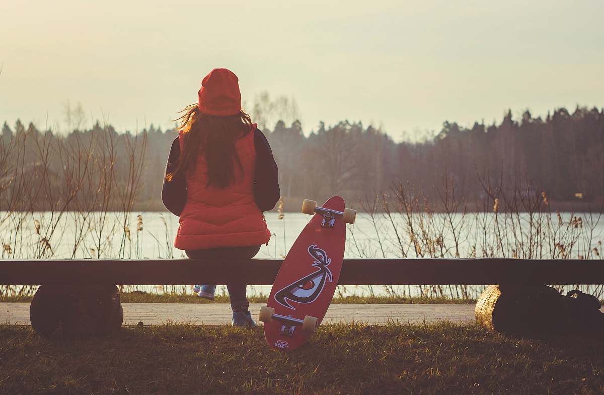 human woman sitting on bench with longboard people