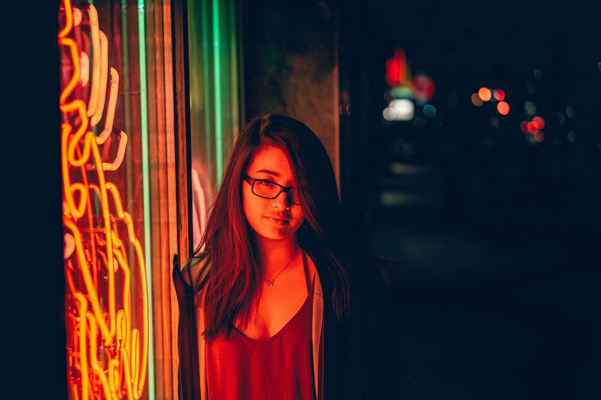 human woman smirking beside glass window with turned on neon signage during night toronto