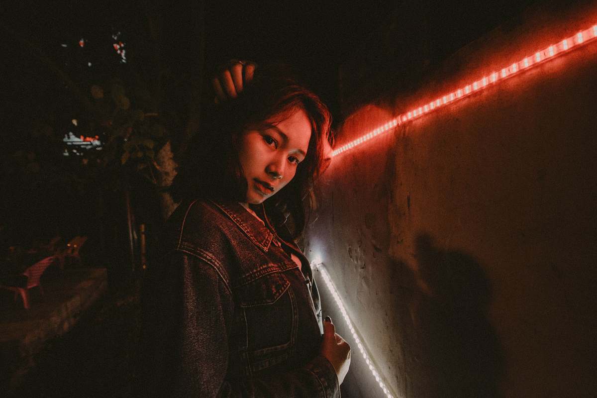 human woman wearing blue denim jacket standing beside red LED people