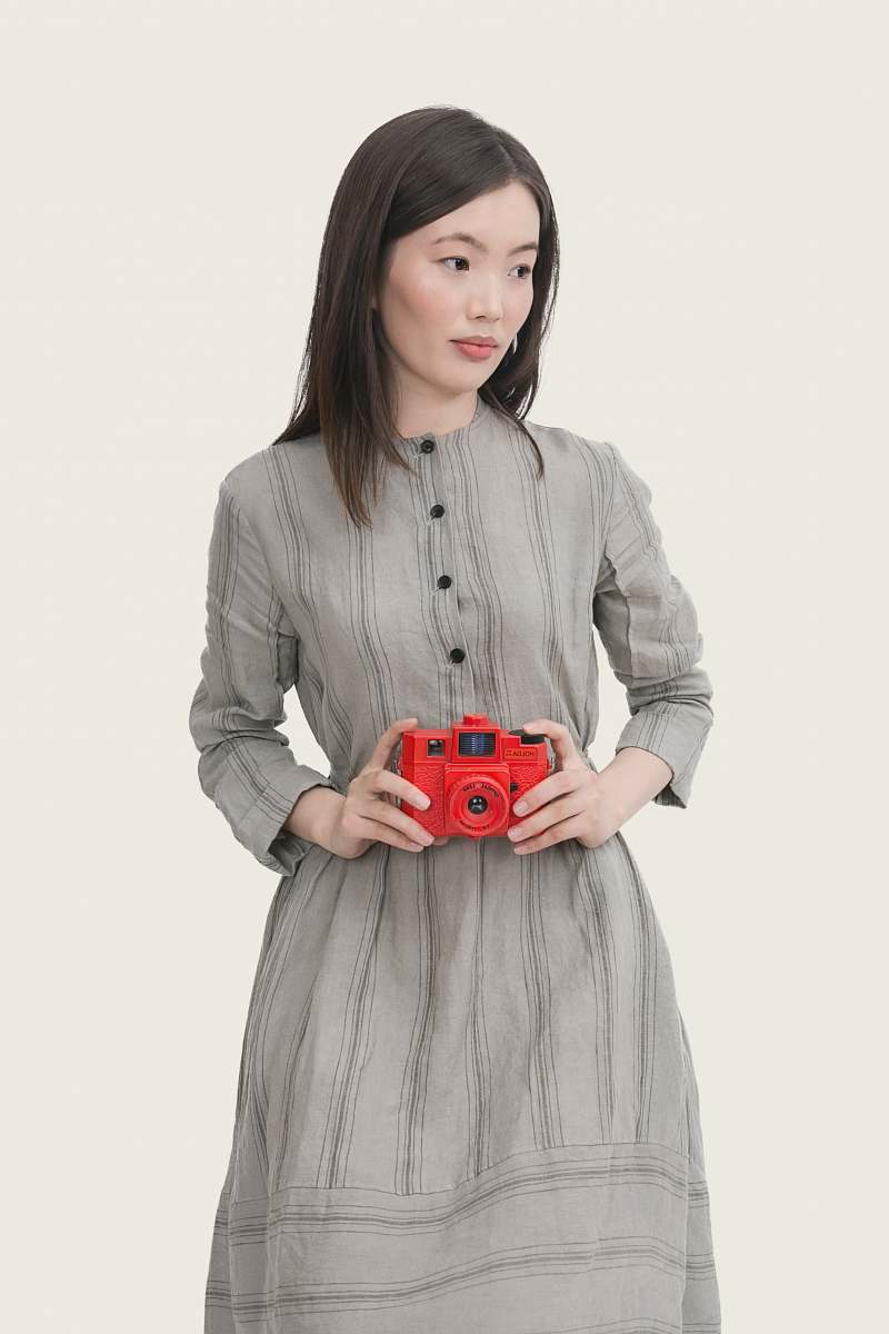 human woman wearing gray striped button-up long-sleeved dress holding red point-and-shoot camera people