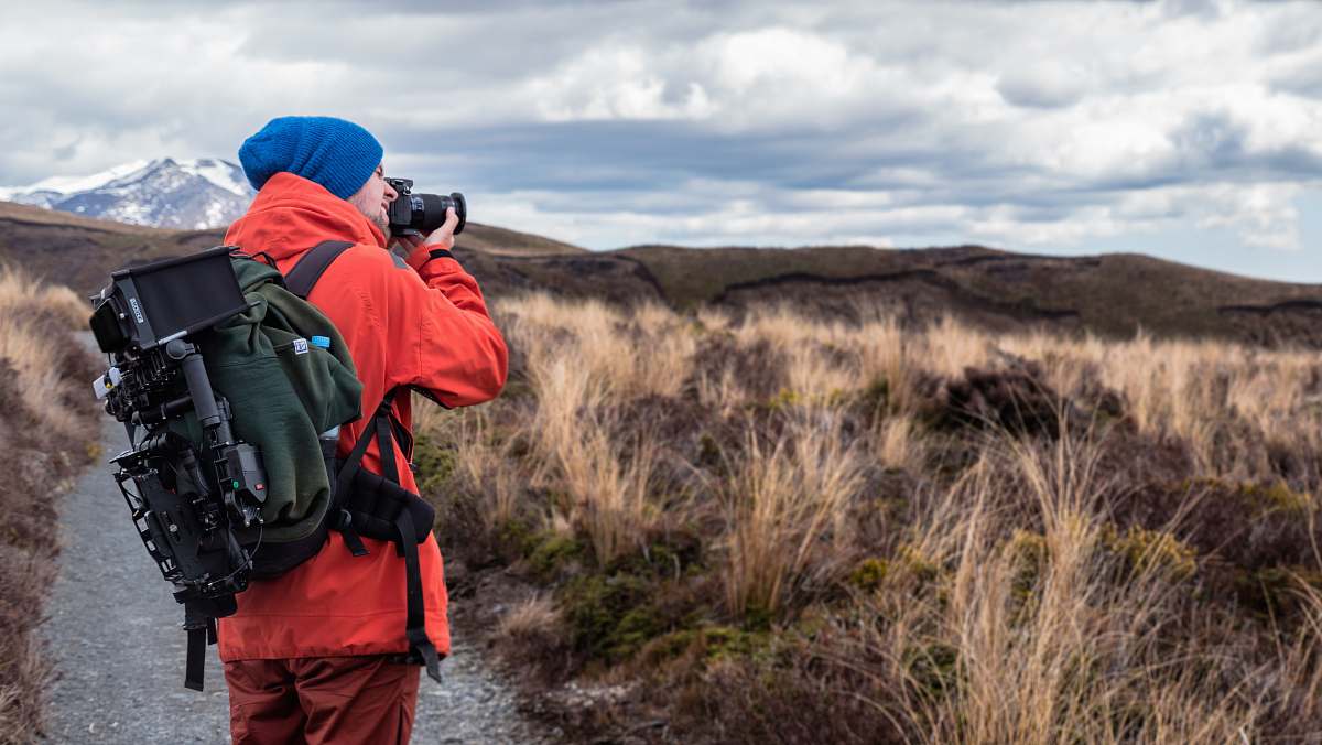 photography person wearing backpack and holding DSLR camera backpack
