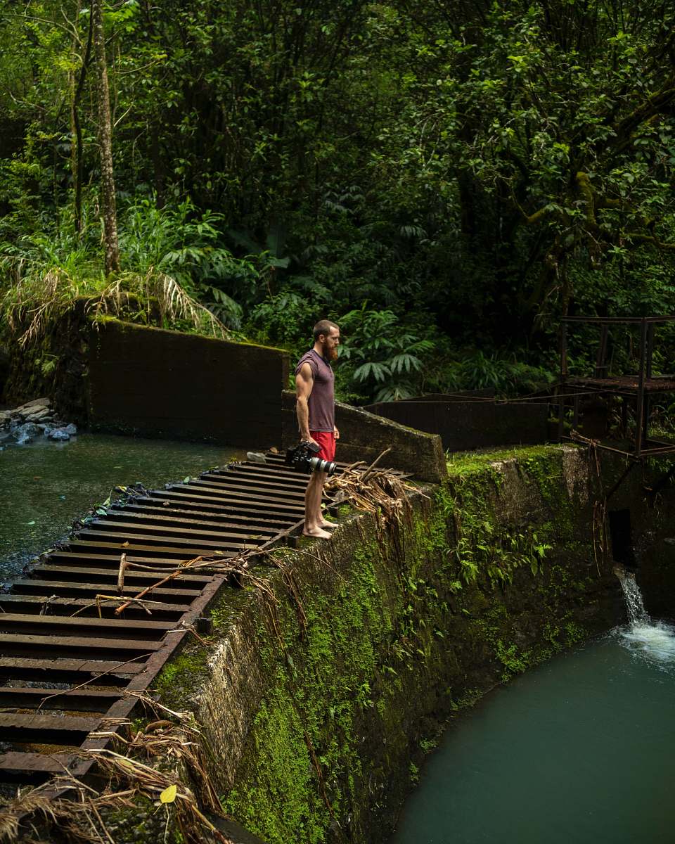 flora man standing on divider rock near waterfalls jar