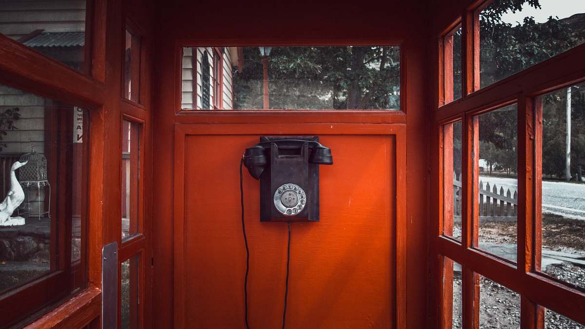 phone black rotary telephone mounted on red wooden wall telephone