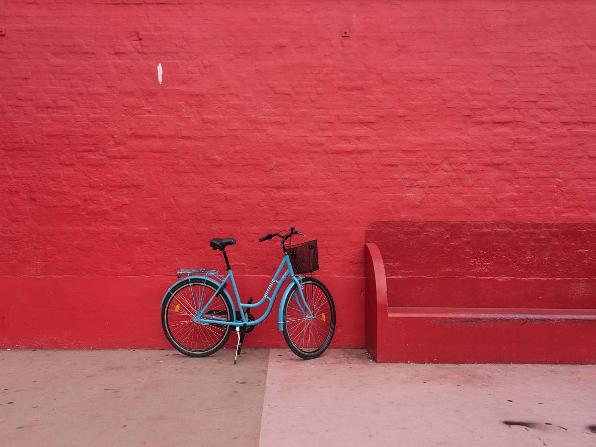 background blue step-through bicycle park beside of red bench bike
