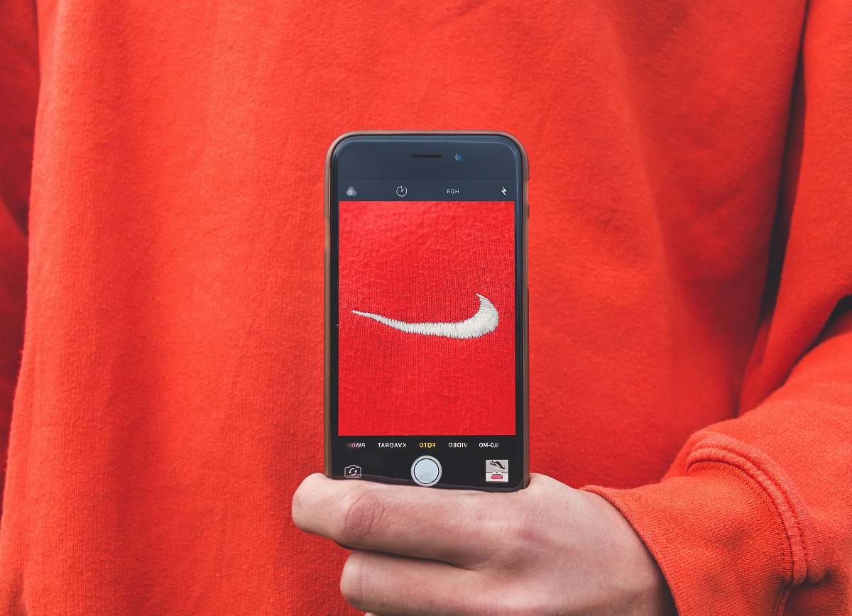 phone person holding iPhone taking picture on Nike label skjød