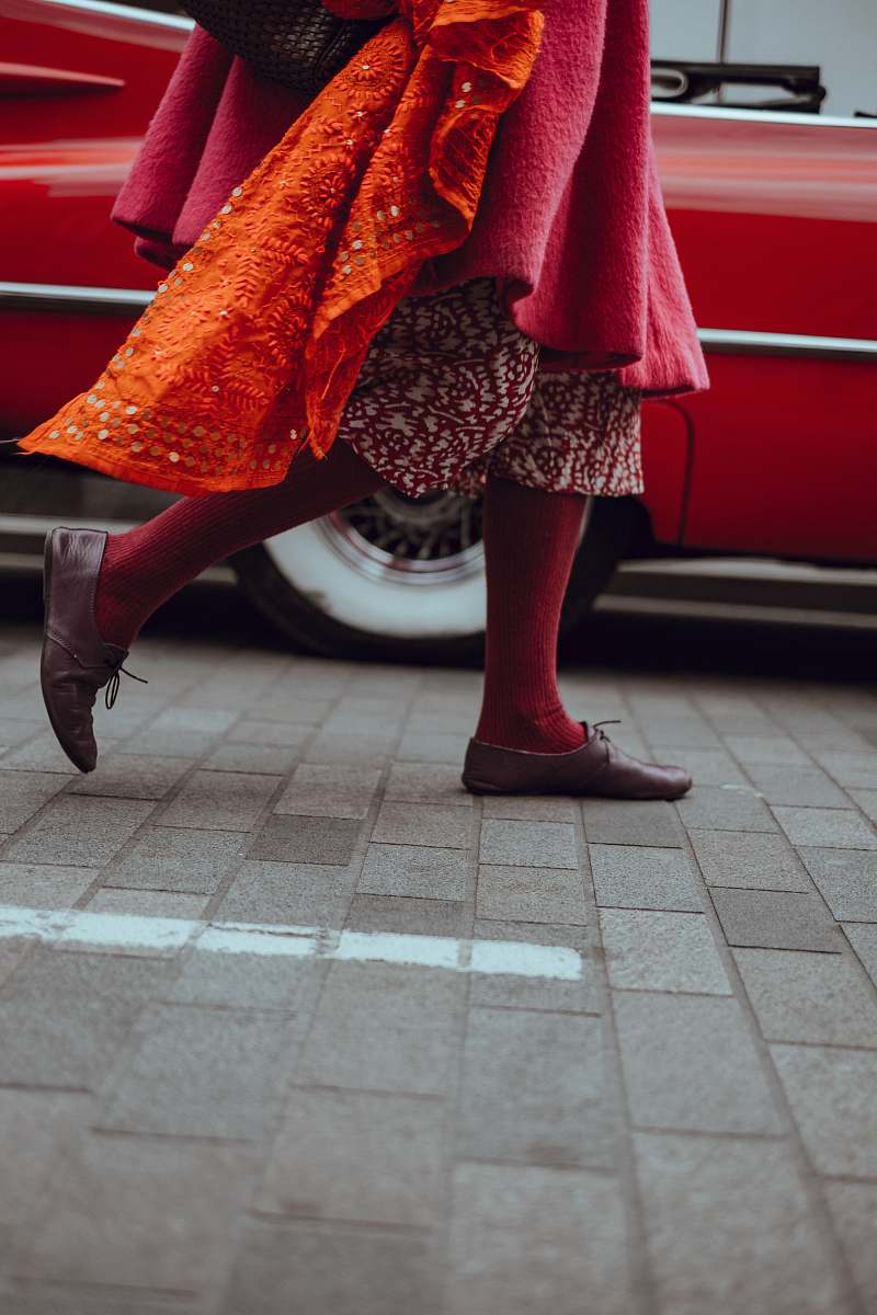 shoe photo of person walking in front of red vehicle walking