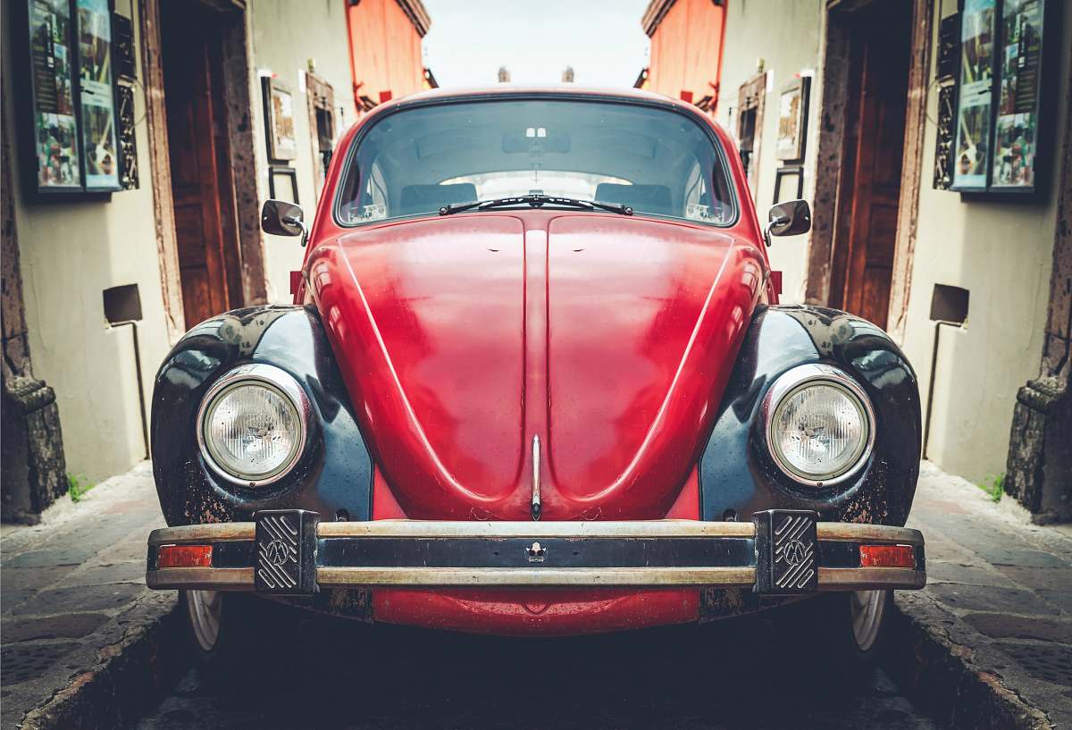 car photo of red and black Volkswagen Beetle in alley vehicle