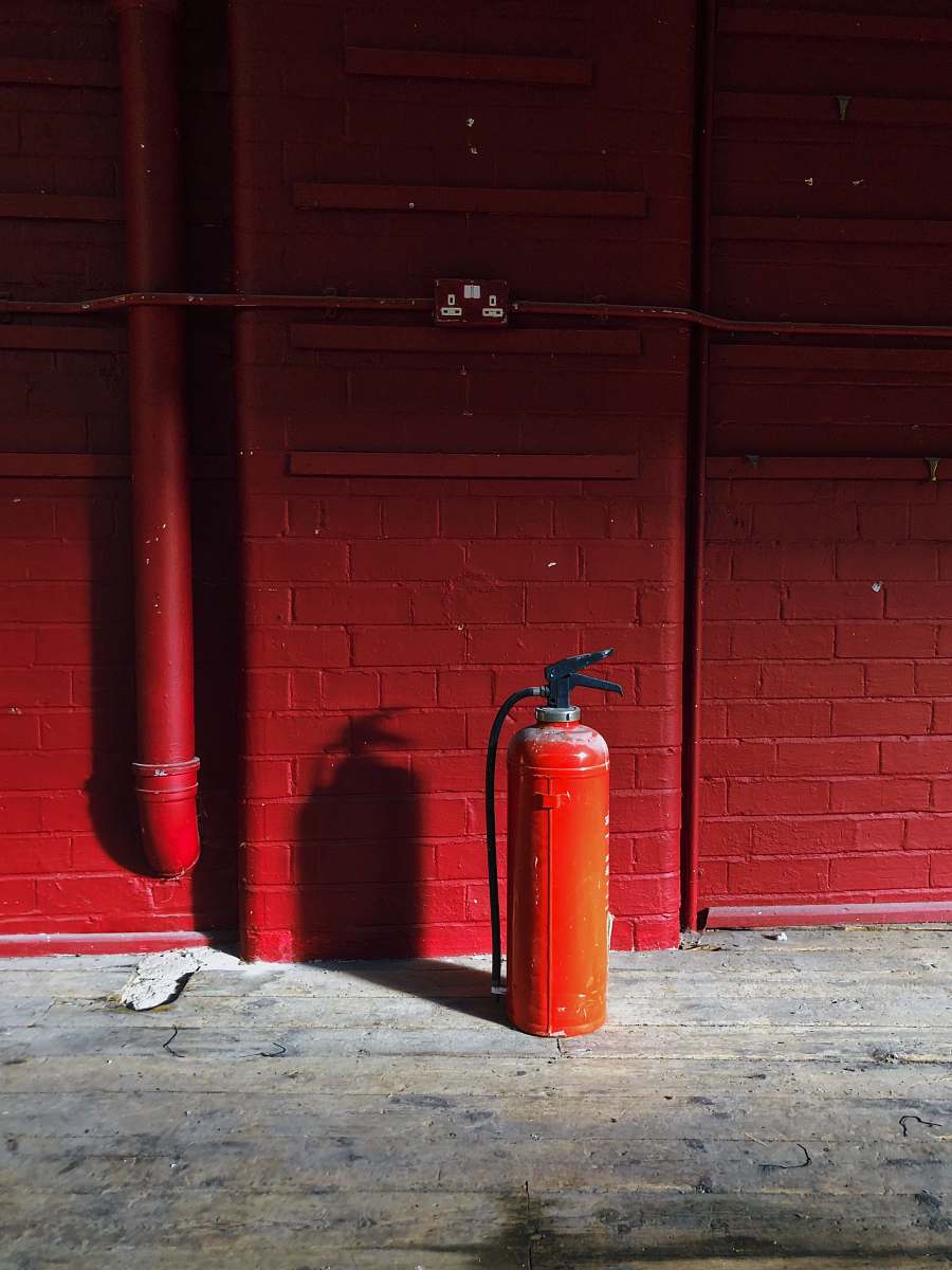 brick red fire extinguisher near red wall wall