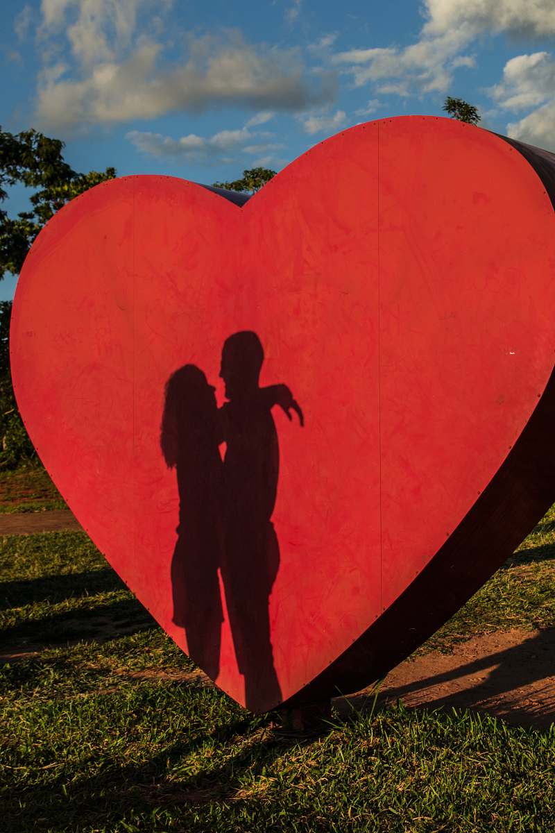 human shadow of coupe hugging near red heart statue person