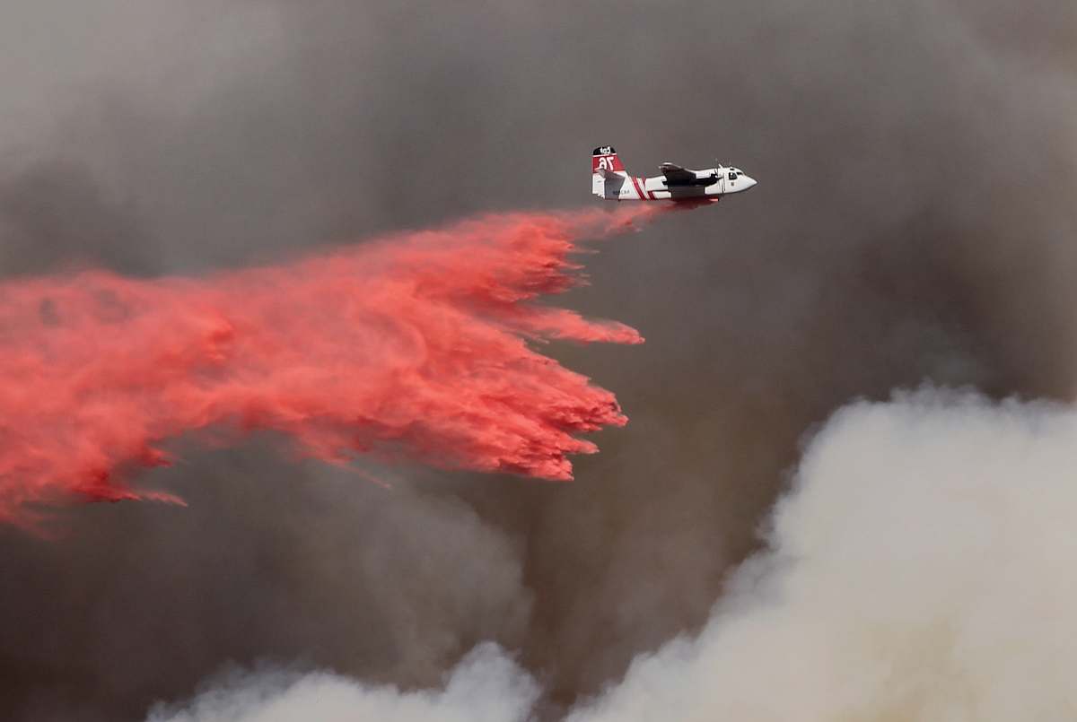 smoke white and red airplane pouring red powder on fire newbury park