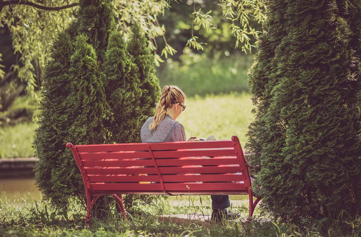 people woman sitting on red wooden bench bench