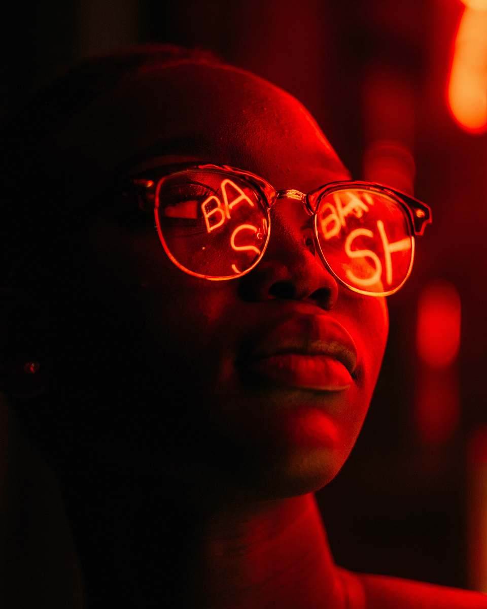 neon woman wearing eyeglasses with red LED signage reflection woman