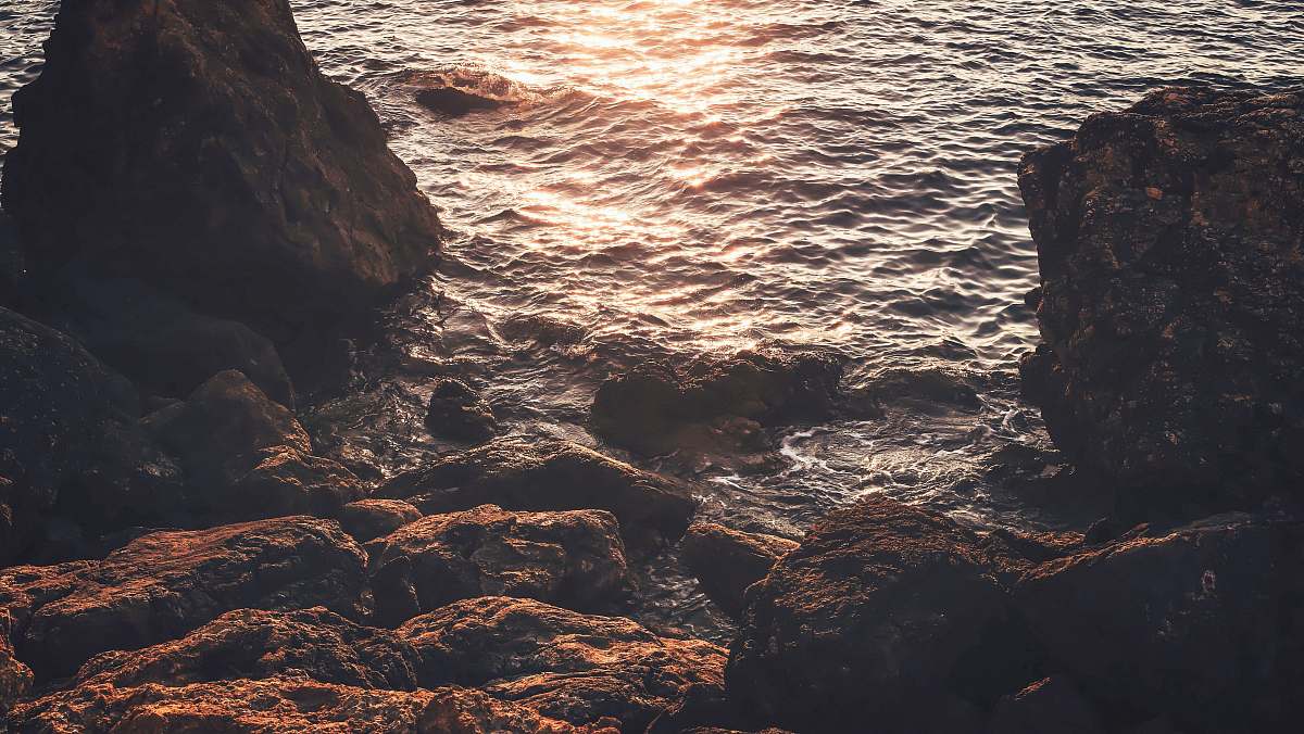 sea rock near seat reflect light on water at daytime ocean