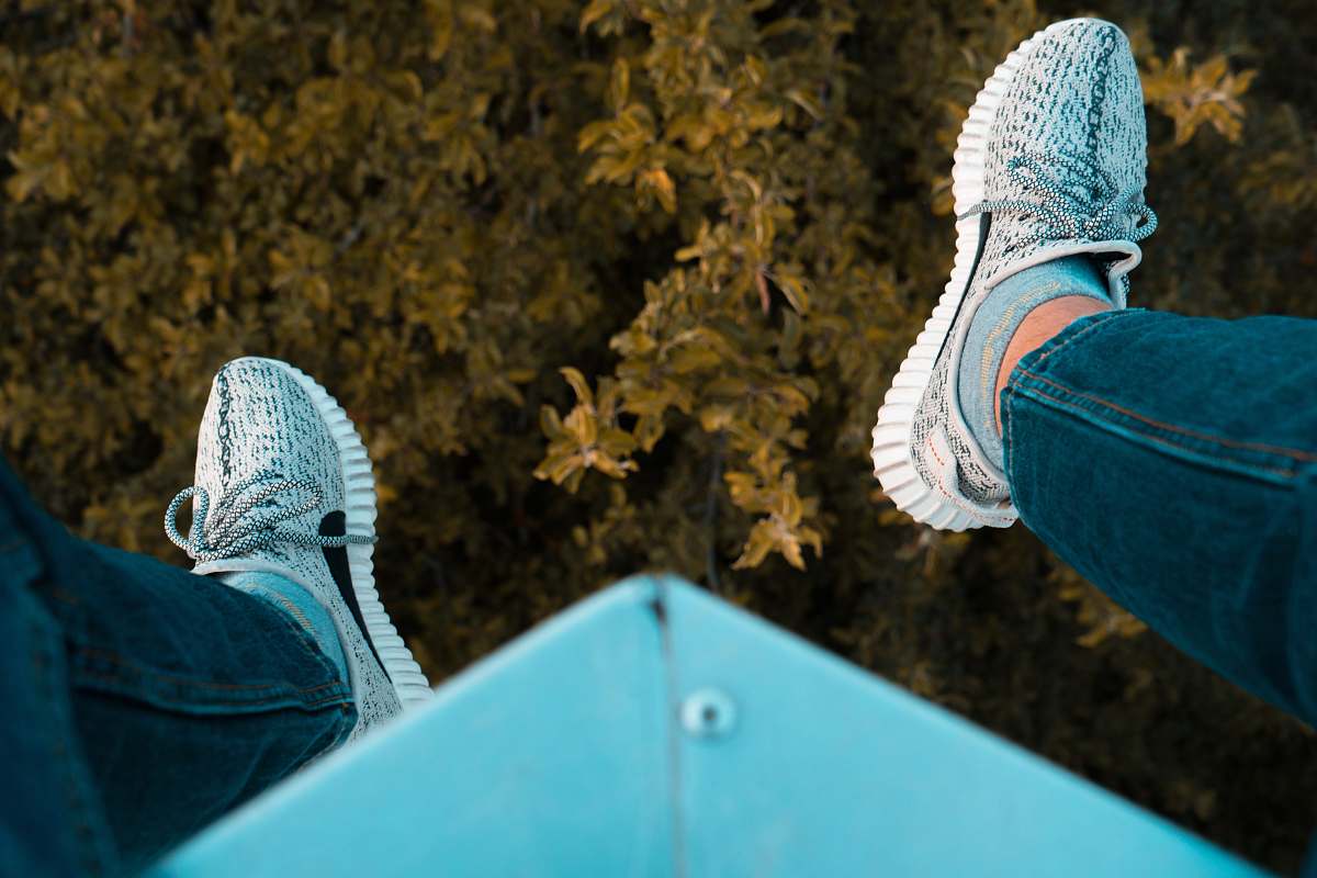 clothing person wearing white adidas sneakers sitting on blue steel frame footwear