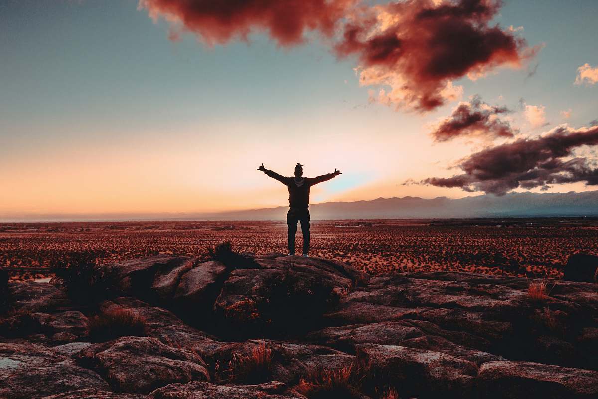 sunrise person standing on rock raising both hands sunset