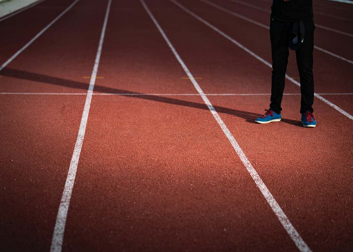 sports person standing on brown and white surface running track
