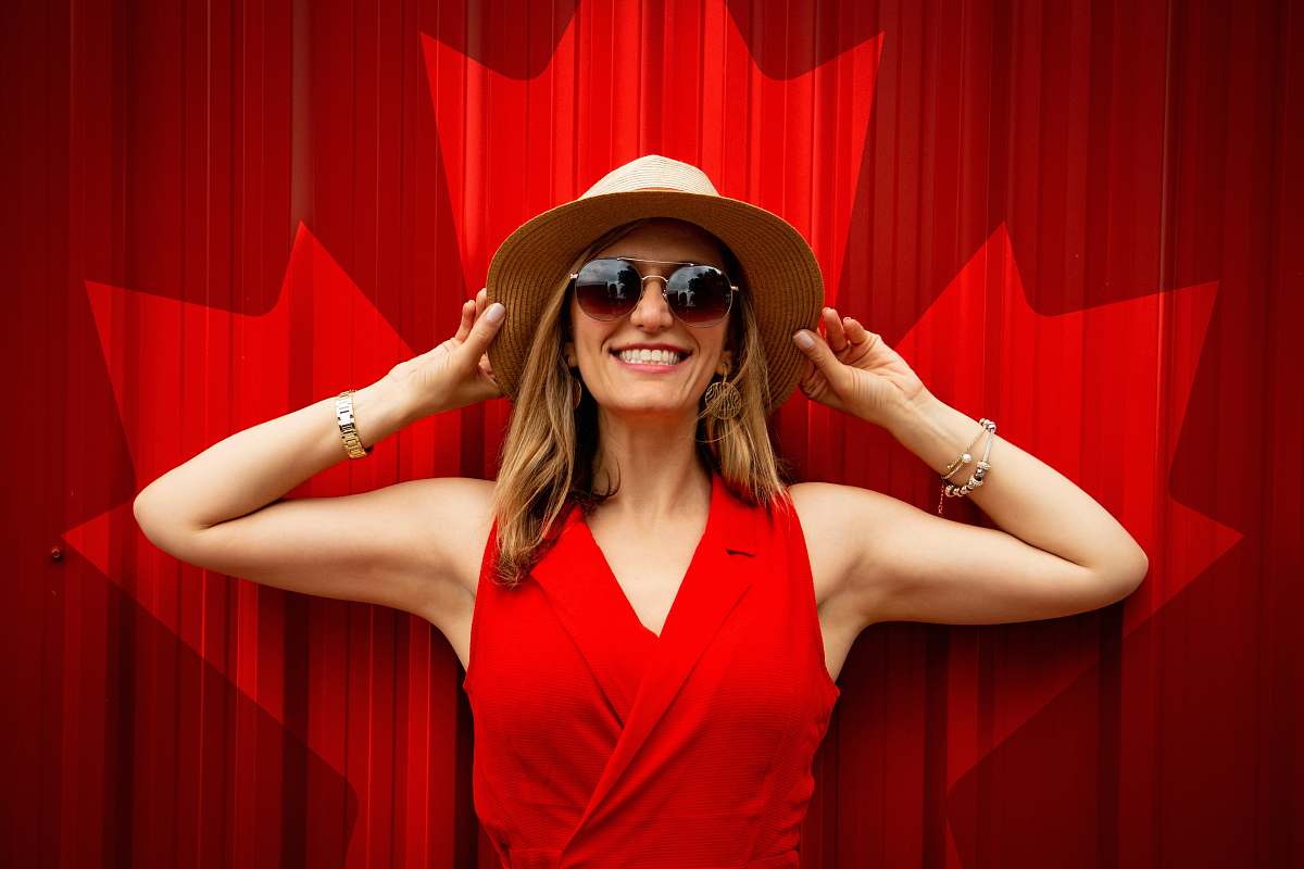 hat woman in red sleeveless top holding her hat while smiling clothing