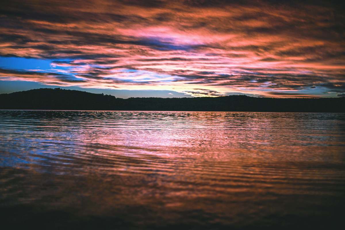 sunrise reflective photography of mountain and body of water water