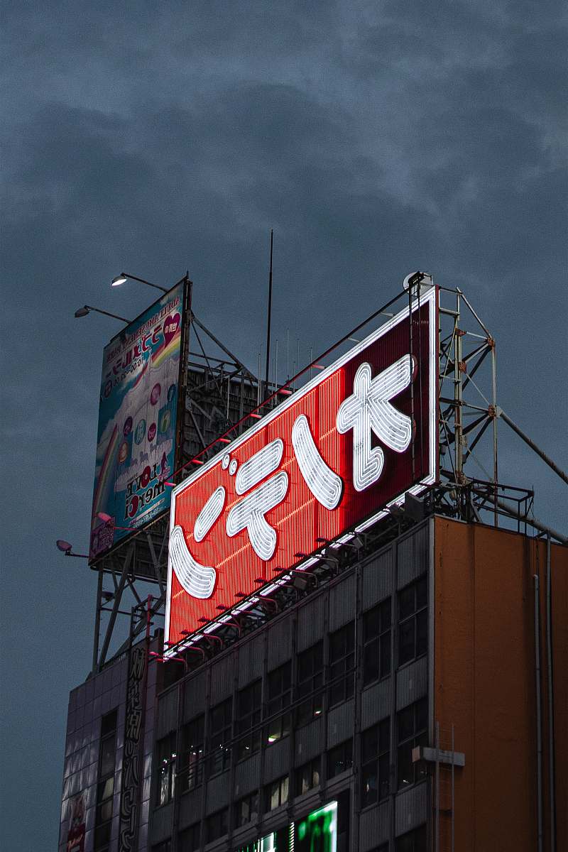 Capture the essence of urban life in Tokyo with this striking image of a white and red tarpaulin advertisement elegantly draped across a contemporary building. The bold colors and modern architecture create a dynamic contrast, making it a perfect visual for marketing campaigns, travel blogs, or cityscape projects. Ideal for showcasing the vibrancy and energy of metropolitan areas, this image embodies the spirit of advertising in a bustling city.
