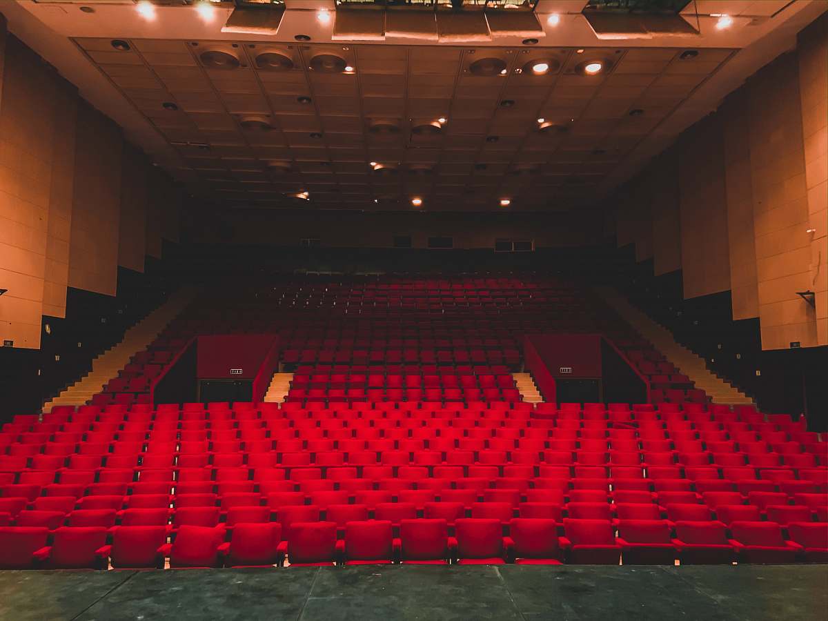hall landscape photography of red seats inside a theater indoors