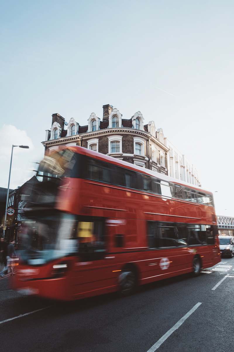 bus red double-deck bus travelling near near brown and white building during daytime vehicle