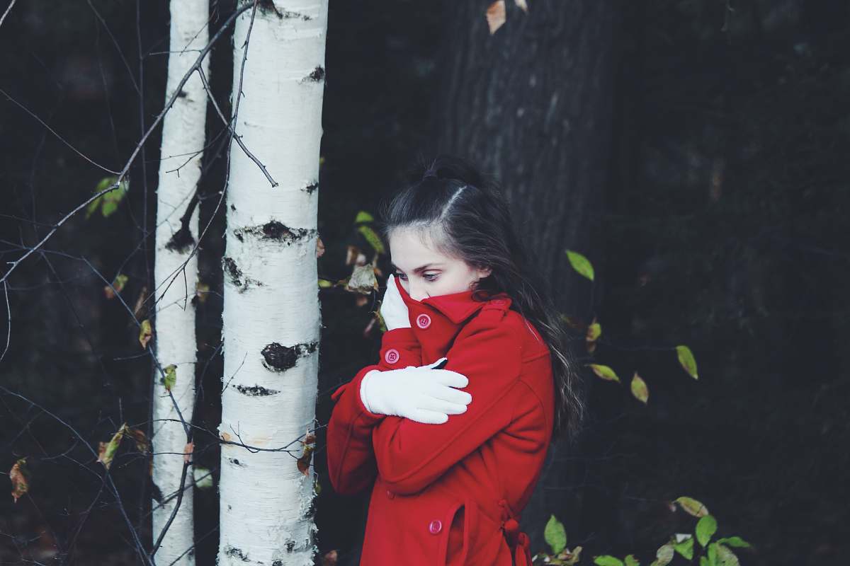 person close-up photography of woman covering mouth by red apparel human