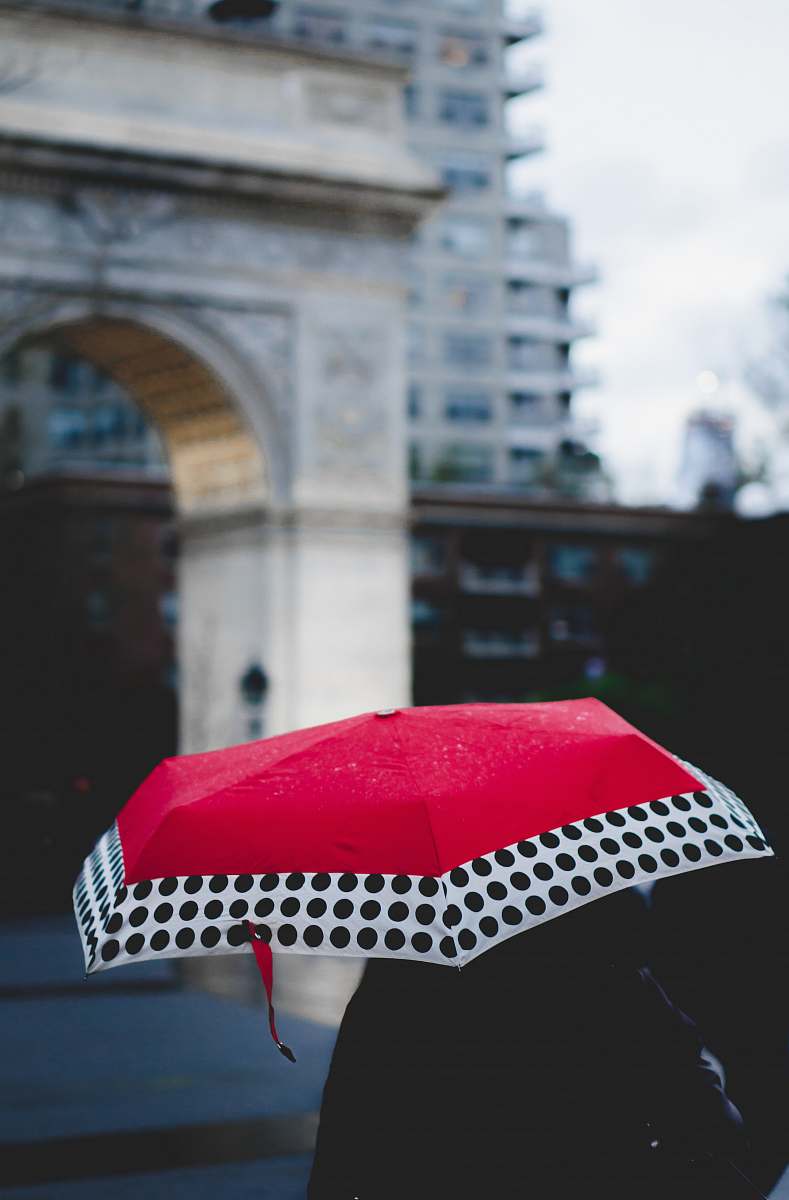 canopy person under red and white umbrella walking near building city