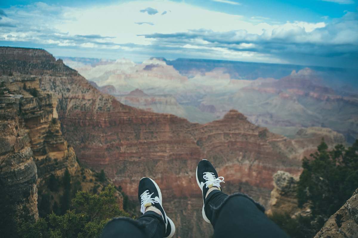canyon person sitting looking through mountain taken under white clouds during daytime nature
