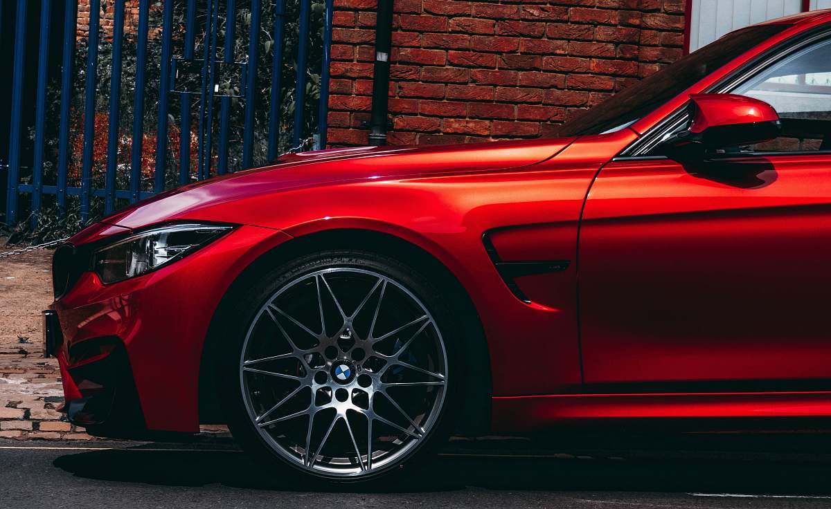 car red BMW vehicle parked at the road near the blue gate brick