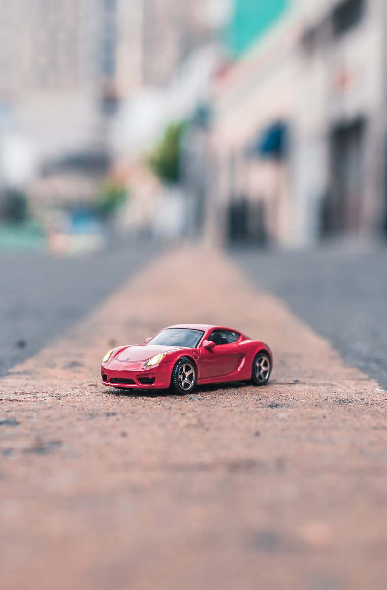car selective focus photography of red coupe scale model on road toluca
