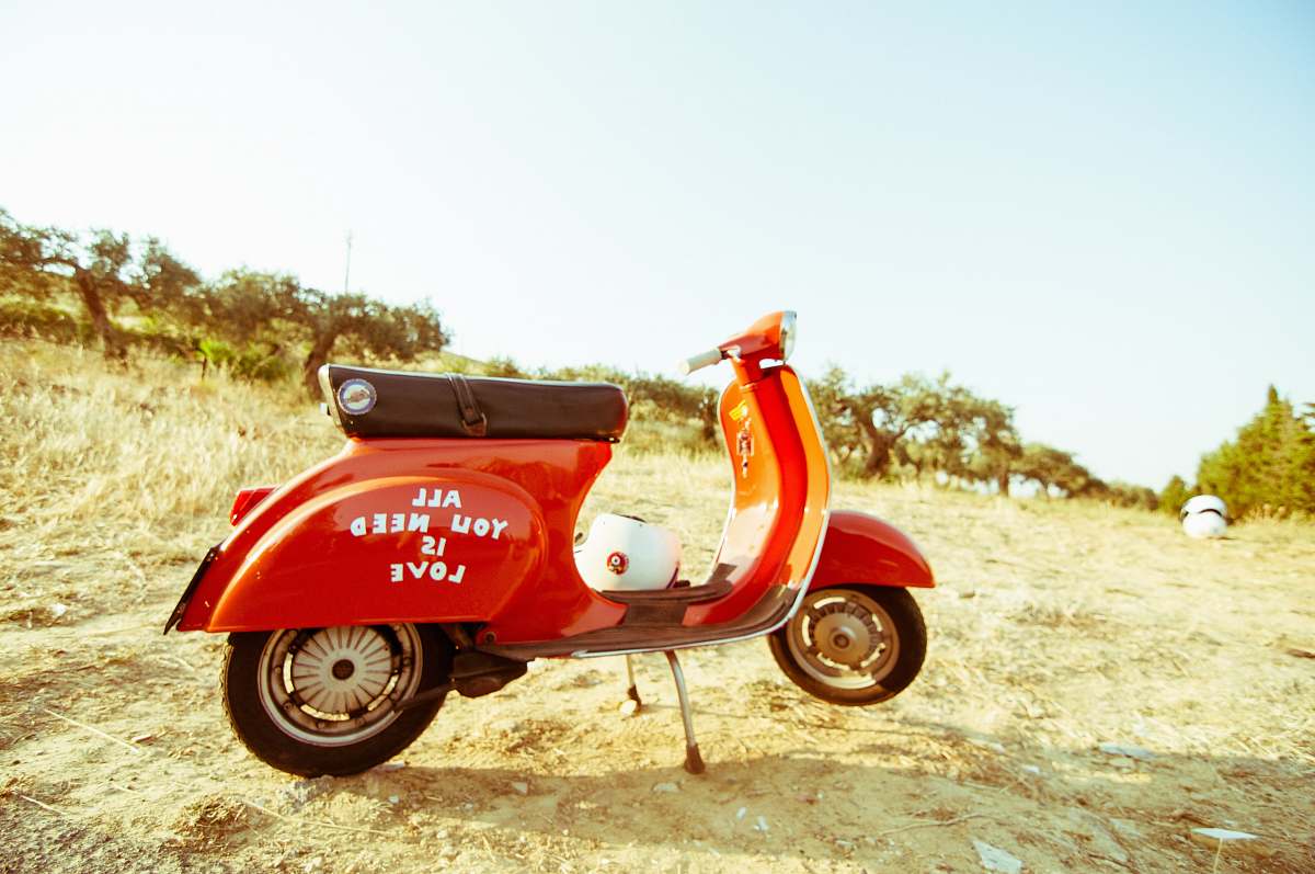 motorcycle red and black motor scooter on open field under clear blue sky motor scooter