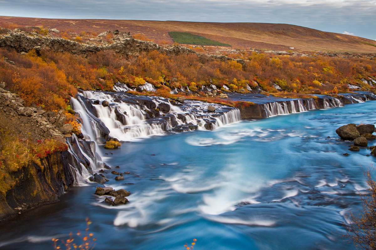 iceland landscape photography of waterfalls surround by brown fiels river