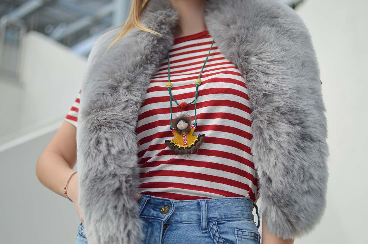 fashion woman wearing red and white striped crew-neck t-shirt and blue denim bottoms outfit with gray faux fur scarf at daytime fur